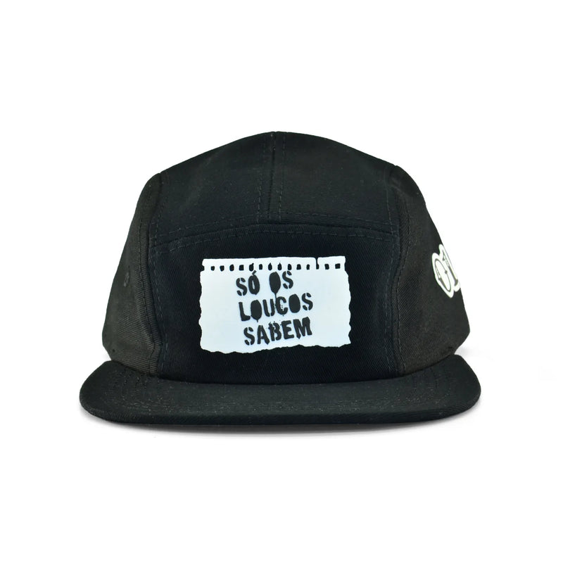 Boné five panel preto com aba curva, estampa branca frontal estilo papel rasgado e frase "Só os loucos sabem" em destaque.