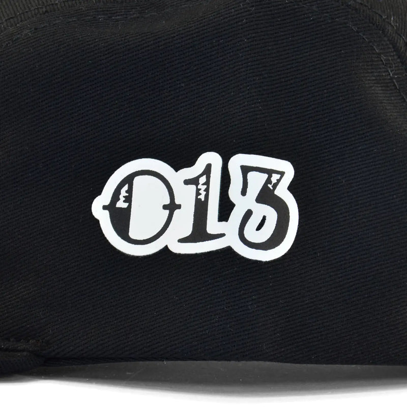 Detalhe do boné five panel preto com tecido canelado e número 013 estilizado em branco centralizado.