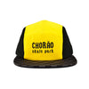 Boné five panel com frente amarela, laterais pretas e aba xadrez, escrito CHORÃO skate park em preto.
