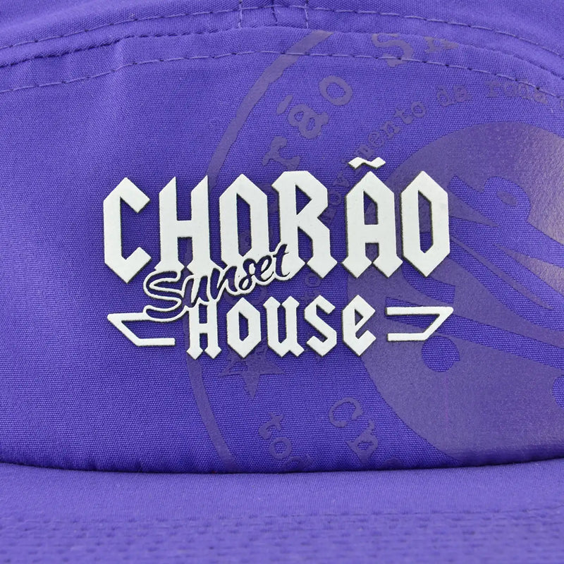 Boné five panel roxo com logo Chorão Sunset House centralizado em branco na parte frontal.