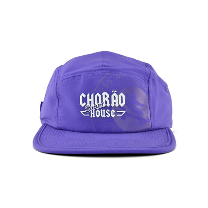 Boné five panel roxo com logo Chorão Sunset House centralizado em branco na frente. Produto para moda casual. 
