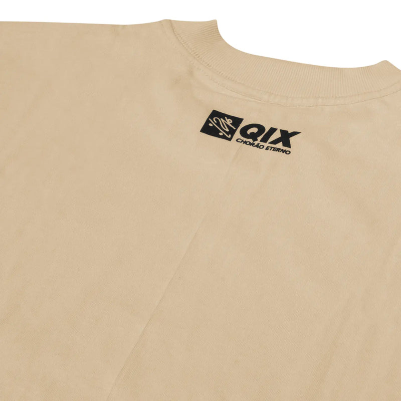 Close do logo próximo à gola na parte de trás da camisa oversized bege.