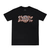 Camiseta preta com design gráfico em destaque no peito, escrita "Charlie Brown Jr", fonte estilizada laranja com detalhes brancos.