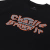 Camiseta preta apresentando design gráfico central com a palavra "Charlie Brown Jr", em fonte angular cinza com contorno laranja vibrante.